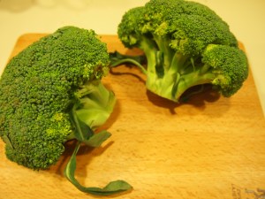 Two large crowns of broccoli with stems and leaves attached