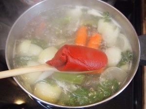 Once the soup is boiling at a rapid pace add in a half can of tomato paste.