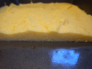 Cooled polenta in a pan, cut to show thickness.
